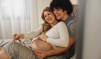 Casal dançando animadamente em uma festa, o homem usa colete e gravata borboleta.